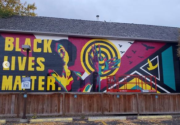 Black Lives Matter mural painting in Kensington black woman with target on her hands and birds flying away from her hands