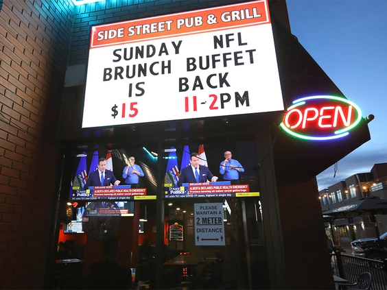 streetside pub and grill sign with tvs beneath in window showing UCP update broadcast